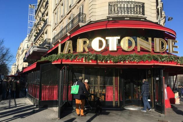 Des passants regardent l'entrée du restaurant La Rotonde à Paris, fermé après l'incendie survenu dans la nuit du 17 au 18 janvier 2020. [Aurore MESENGE / AFP]