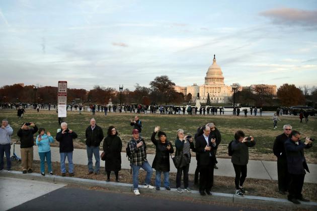 Des gens regardent le passage du corbillard transportant la dépouille du 41e président des Etats-Unis, George Herbert Walker Bush, à Washington le 3 décembre 2018 [Alex Brandon / POOL/AFP]