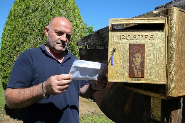 Bernard Colin, le gardien du cimetière de l'Ouest à Charleville-Mézières depuis 37 ans, sort une lettre de la boîte aux lettres dédiée au poète Arthur Rimbaud, le 21 juin 2019 [FRANCOIS NASCIMBENI / AFP]