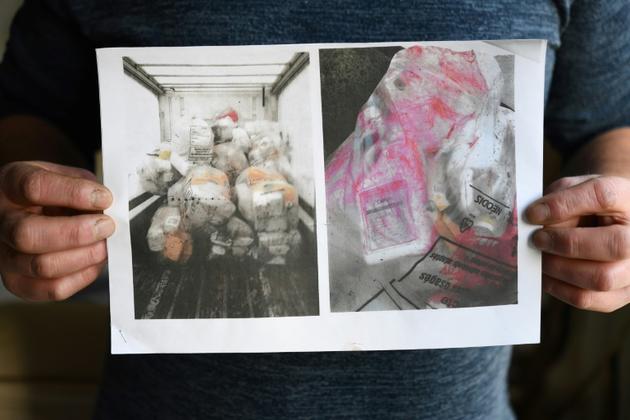 Noel Pouliquen montre des photos de déchets de produits toxiques stockés dans un camion [Fred TANNEAU / AFP]