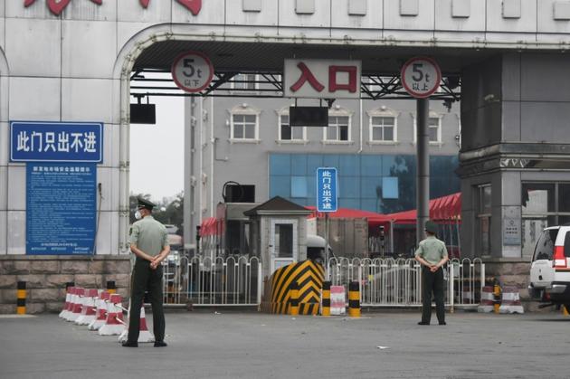 Des policiers chinois devant l'entrée du marché Xinfadi fermé, le 13 juin 2020 à Pékin, après l'apparition d'un nouveau foyer de coronavirus [GREG BAKER / AFP]