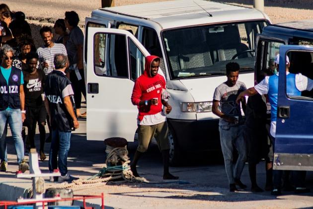 Vingt-sept migrants mineurs non-accompagnés, secourus par le navire de l'ONG espagnole Proactiva Open Arms, sont conduits vers des véhicules de la police italienne avant de quitter le port de Lampedusa où ils ont débarqué le 17 août 2019 [Alessandro SERRANO / AFP]