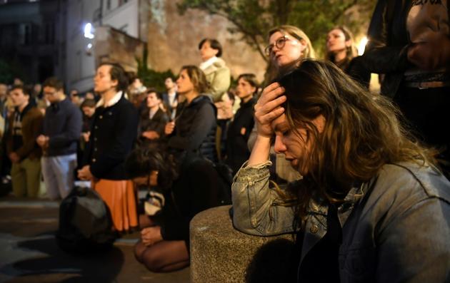 Des fidèles catholiques prient devant Notre-Dame de Paris, le 15 avril 2019 [ERIC FEFERBERG / AFP/Archives]