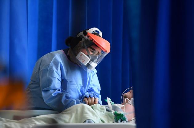 Une soignante réconforte un patient atteint par le coronavirus, le 5 mai 2020 dans un hôpital de Cambridge, au Royaume-Uni [Neil HALL / POOL/AFP]