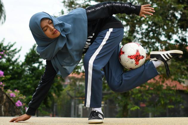 Qhouirunnisa' Endang Wahyudi, 18 ans, fait une figure de football freestyle, dans un parc à Klang, près de Kuala Lumpur le 11 juillet 2018 [MOHD RASFAN / AFP]