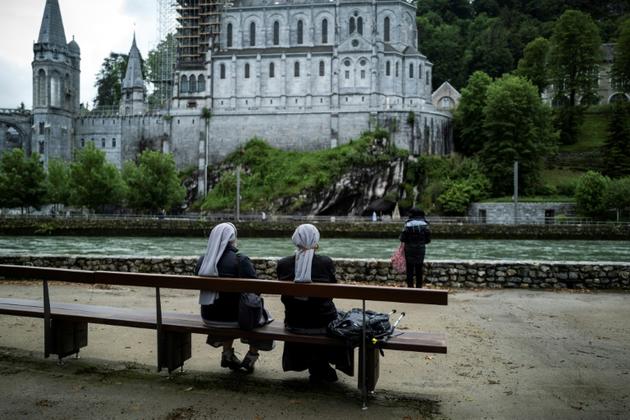 Des pèlerins devant la basilique Notre-Dame du Rosaire avant la réouverture du sanctuaire de Lourdes, fermé pour la première fois de son histoire pendant deux mois, pour cause d'épidémie, le 16 mai 2020 à Lourdes [Lionel BONAVENTURE / AFP]