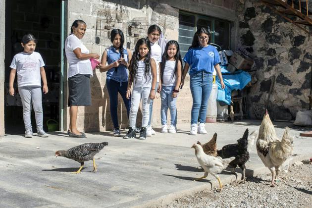 Atanacia Carvete apprend à ses petites-filles nées et vivant aux Etats-Unis (de gauche à droite) Eleny, Briana, Jocelyn, Dianna, Jasmin et Vanessa, à nourrir les poules, à Teopantlan, dans l'Etat mexicain de Puebla, le 19 juillet 2018 [PEDRO PARDO / AFP]