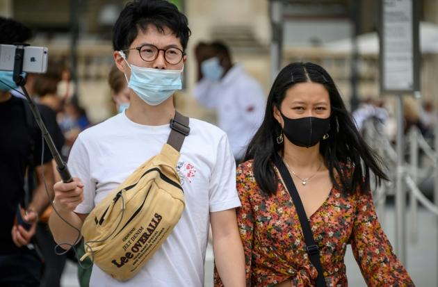 Des touristes asiatiques portent un masque de protection, le 15 août 2020 à Paris  [BERTRAND GUAY / AFP]