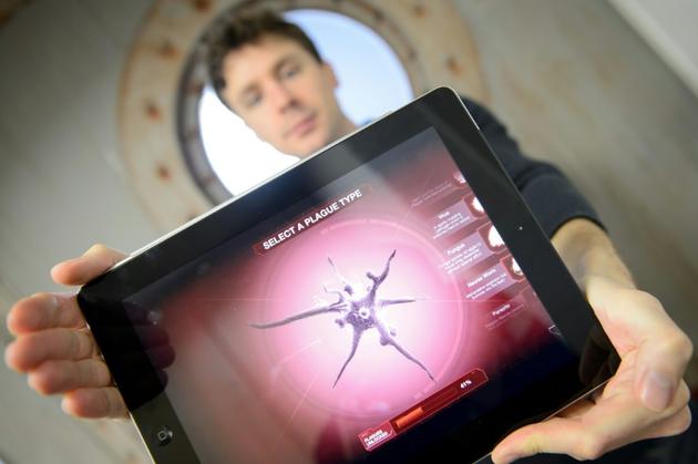 Le créateur du jeu vidéo Plague Inc., James Vaughan, avec une tablette qui montre une image du jeu, le 7 novembre 2014 à Londres  [LEON NEAL / AFP/Archives]