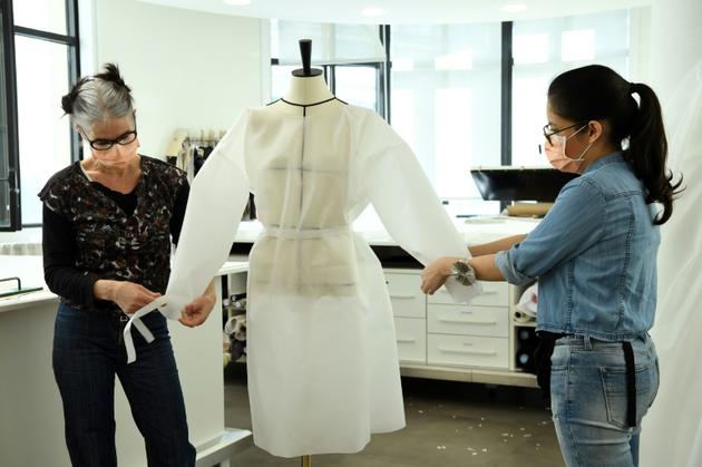 Deux couturières chez Louis Vuitton confectionnent un modèle de blouse qui doit etre porté par des infirmières, dans leur atelier à Paris, le 10 avril 2020 [BERTRAND GUAY / AFP/Archives]