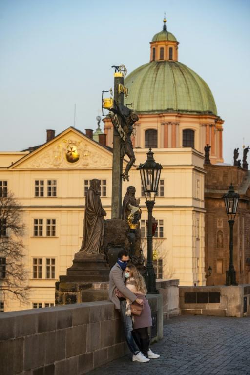 Une femme et un homme portant des masques de protection contre le nouveau coronavirus, enlacés à Prague le 28 mars 2020 [Michal Cizek / AFP]