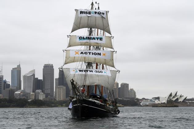 Un bateau portant la bannière "Rise for climate" (Debout pour le climat) entre dans le port de Sydney, en Australie, le 8 septembre 2018, au début de la journée d'action mondiale pour le climat [Saeed KHAN / AFP]