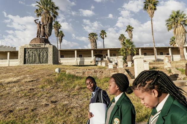 Des écolières de Namibie passent le 20 juin 2017 devant un monument à la mémoire des victimes du génocide contre les Herero et les Nama en 1904<br />
 [GIANLUIGI GUERCIA / AFP/Archives]