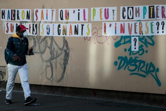Un passant devant un mur de l'hôpital Lariboisière à Paris, où figure le message 