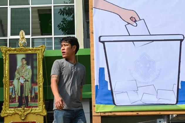 Un homme passe près d'un portrait du roi de Thaïlande Maha Vajiralongkorn et d'une affiche électorale à Bangkok, le 23 mars 2019 [Jewel SAMAD / AFP]