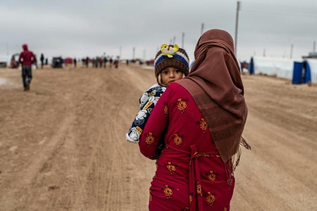 Une femme syrienne porte un enfant dans un camp pour déplacés, près de Hassaké, dans le nord-est de la Syrie en guerre, le 17 février 2020  [Delil SOULEIMAN / AFP]