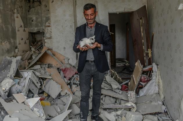 Un homme tient un chaton trouvé dans les ruines de son apartement après un bombardement, le 10 octobre 2020 à Tartar, en Azerbaïdjan [Bulent Kilic / AFP]