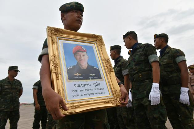 Un soldat thailandais porte le portrait de Saman Kunan, un ancien plonguer de la marine thaïlandaise mort lors d'une opération de ravitaillement des 12 enfants bloqués dans la grotte de Tham Luang, le 6 juillet 2018 [Panumas SANGUANWONG / THAI NEWS PIX/AFP]
