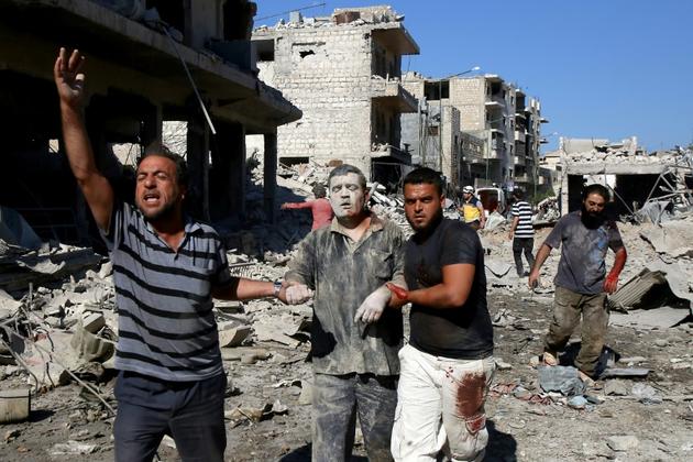 Accompagné de deux hommes, un Syrien sort des décombres d'un immeuble visé par un bombardement, à Maaret al-Noomane, dans le nord-ouest de la Syrie, le 22 juillet 2019<br />
 [Abdulaziz KETAZ / AFP]