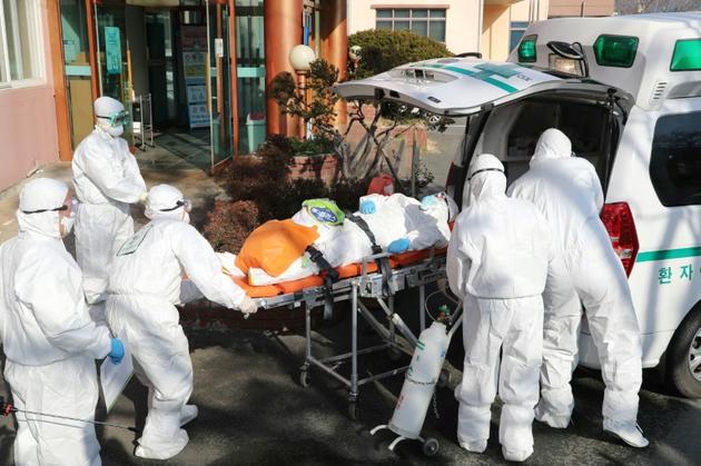Le personnel médical transfère un patient soupçonné d'être porteur du coronavirus de l'hôpital Daenam à Cheongdo le 21 février 2020 [- / YONHAP/AFP]