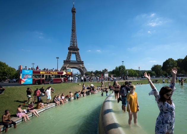 Des gens se rafraîchissent dans une fontaine au pied de la Tour Eiffel le 2 août 2018 à Paris [GERARD JULIEN / AFP]