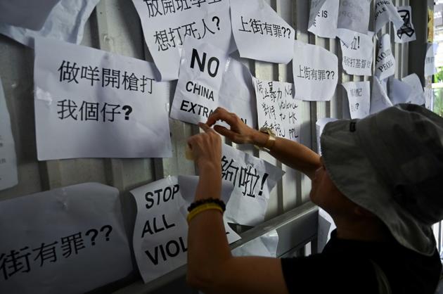 Un homme placarde des slogans dénonçant le projet d'autoriser les extraditions vers la Chine sur un mur près du Conseil législatif à Hong Kong, le 14 juin 2019 [Hector RETAMAL / AFP]