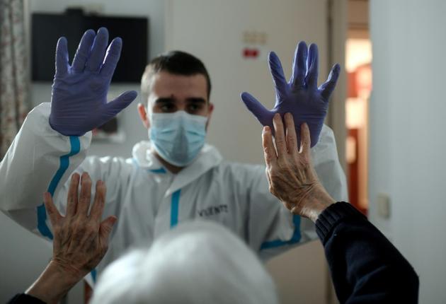 Un soignant avec un résident d'une maison de retraite le 24 avril 2020 à Madrid [OSCAR DEL POZO / AFP]