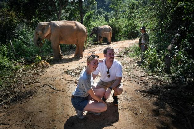 Des touristes se font photographier à proximité de deux éléphants dans le parc de ChangChill, près de Chiang Mai, le 6 novembre 2019 en Thaïlande [Lillian SUWANRUMPHA / AFP]