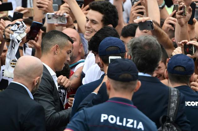 La recrue star de la Juventus Cristiano Ronaldo signe des autographes, à son arrivée au centre médical du club, le 16 juillet 2018 à Turin [Miguel MEDINA / AFP]