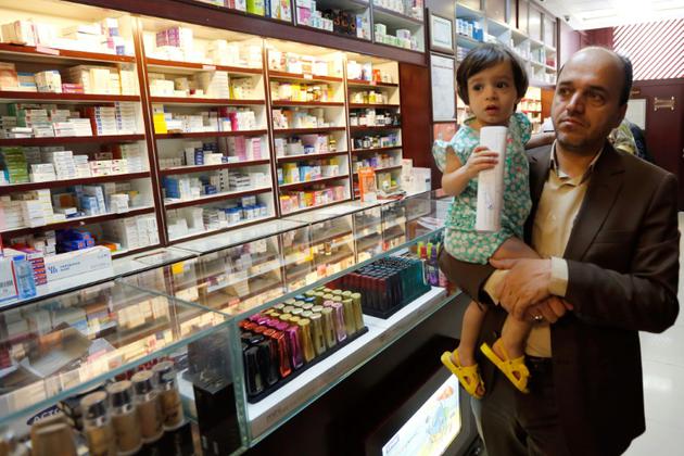 Un client d'une pharmacie de Téhéran portant dans ses bras un enfant, le 11 septembre 2018 dans la capitale iranienne [STRINGER / afp/AFP]