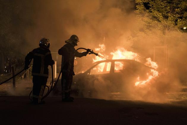 Un pompier lutte contre les flammes d'une voiture incendiée dans le quartier Malakoff de Nantes, le 4 juillet 2018 [SEBASTIEN SALOM GOMIS / AFP]