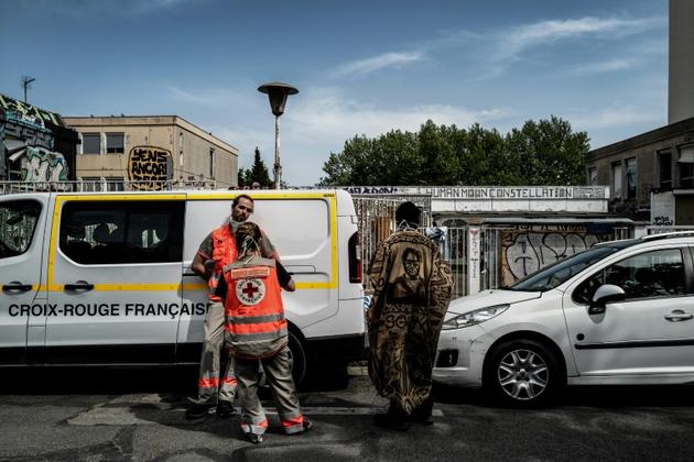 Un homme discute avec des membres de la Croix-Rouge devant la cour d'une école temporairement reconvertie en centre d'accueil pour migrants, le 16 avril 2020 à Lyon   [JEFF PACHOUD / AFP/Archives]