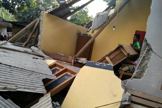 Un Indonésien dans les décombres d'une maison de Lombok en Indonésie après un tremblement de terre, le 29 juillet 2018 (Photo transmise par l'agence indonésienne de gestion des catastrophes) [Handout / Nusa Tenggara Barat Disaster Mitigation Agency/AFP]