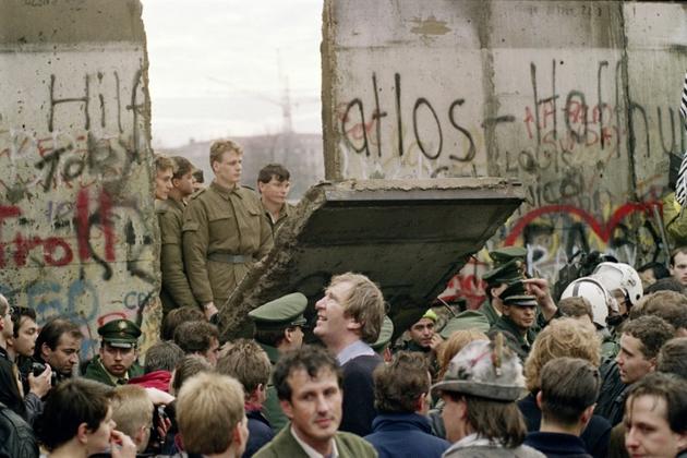 Des Berlinois de l'est regardent des soldats ouest-allemands en train d'abattre des pans du Mur à Berlin pour créer un nouveau point de passage, le 11 novembre 1989 [Gerard MALIE / AFP/Archives]