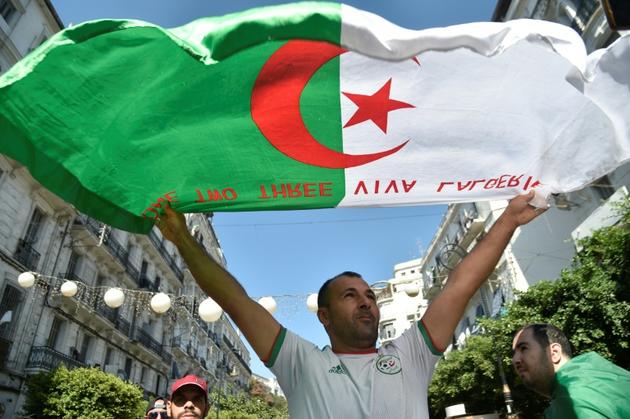 Un Algérien agite un drapeau national lors d'une manifestation contre la classe dirigeante dans la capitale Alger le 27 septembre 2019, pour le 32e vendredi consécutif depuis le début de la contestation<br />
 [RYAD KRAMDI                         / AFP]