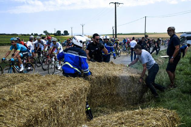 Des gendarmes libèrent la chaussée brièvement bloquée par les agriculteurs à coup de meules de foin durant la 14e étape du Tour, le 24 juillet 2018 [Jeff PACHOUD / AFP]