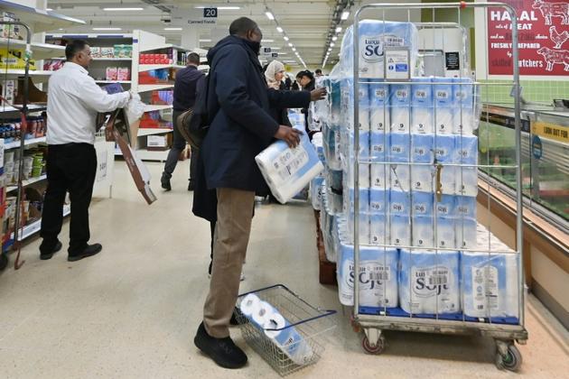 Un homme achète du papier toilette dans un magasin à Londres, le 14 mars 2020 [JUSTIN TALLIS / AFP]