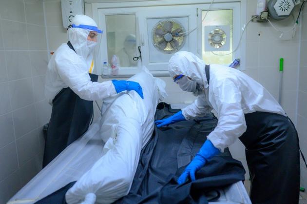 Des personnels funéraires en combinaison de protection préparent le corps d'une personne décédée du coronavirus à la morgue du cimetière d'Istanbul, le 21 mai 2020 en Turquie [BULENT KILIC / AFP]