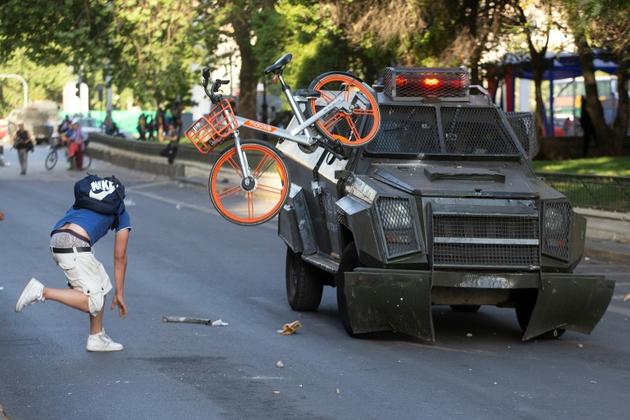 Un manifestant s'en prend aux forces de l'ordre, le 18 octobre 2019 à Santiago [CLAUDIO REYES / AFP]