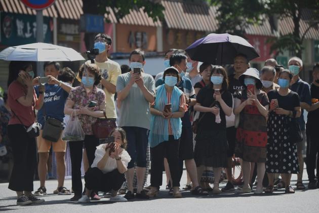 Un flot de curieux prennent des photos depuis une route menant au consulat américain de Chengdu, dans la province du Sichuan, dans le sud-ouest de la Chine, le 27 juillet 2020 [Noel Celis / AFP]