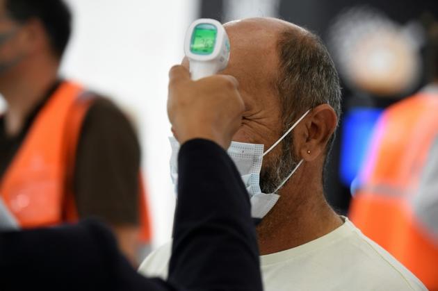 Contrôle de la température d'un passager à l'aéroport d'Orly le 26 juin 2020 [ERIC PIERMONT / AFP]