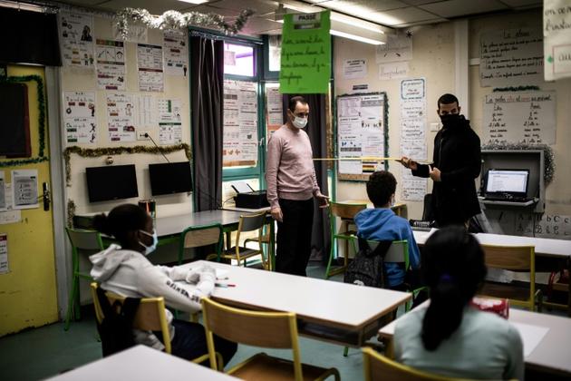 Des enseignants montrent à leurs élèves comment respecter les distances sanitaires, à l'école Saint-Exupéry de La Courneuve (Seine-Saint-Denis), le 14 mai 2020  [Martin BUREAU / AFP]
