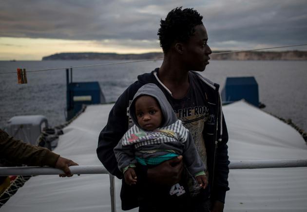 Un migrant tenant un bébé regarde la côte maltaise depuis le pont du Sea Watch 3, le 9 janvier 2019 [FEDERICO SCOPPA / AFP]