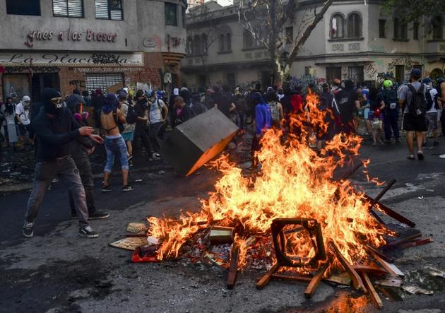 Des manifestants allument un bûcher le 14 novembre 2019 à Santiago lors de protestations anti-gouvernementales et de la commémoration de la mort d'un Mapuche tué par la police un an auparavant [Martin BERNETTI / AFP]