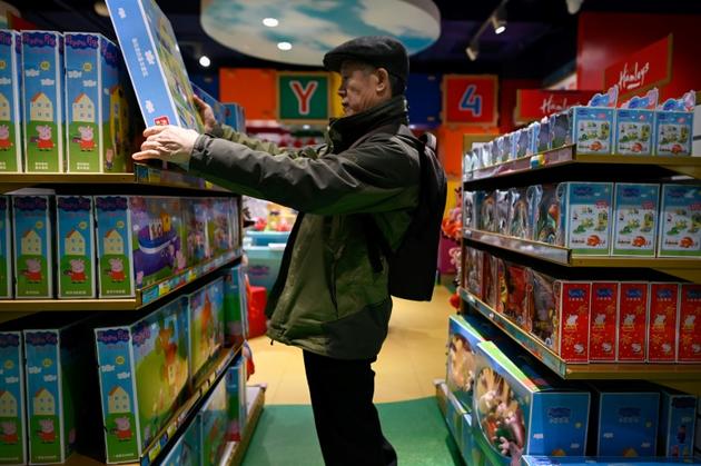 Un homme regarde un jouet Peppa Pig dans un magasin, le 25 janvier 2019 à Pékin [WANG Zhao / AFP/Archives]