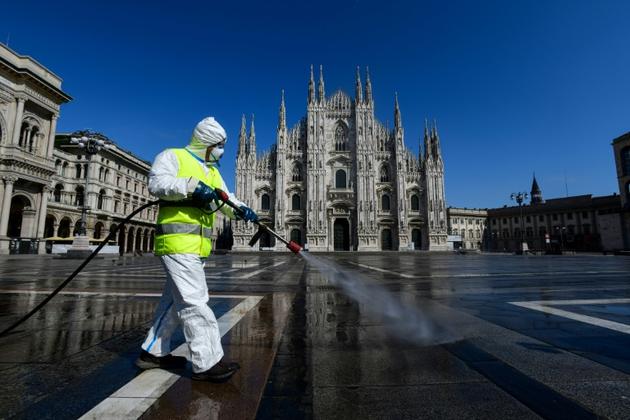 Un employé des services de l'environnement vaporise des produits désinfectants  Piazza Duomo à Milan, le 31 mars 2020 [Piero Cruciatti / AFP]