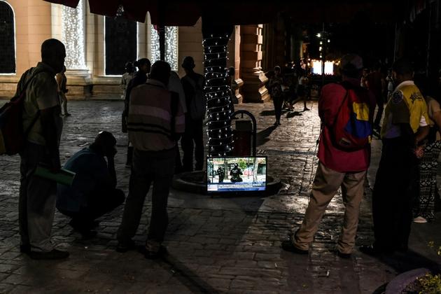 Des passants regardent la télévision dans la rue, place Bolivar, le 13 décembre 2019 à Caracas, au Venezuela [Yuri Cortez / AFP]