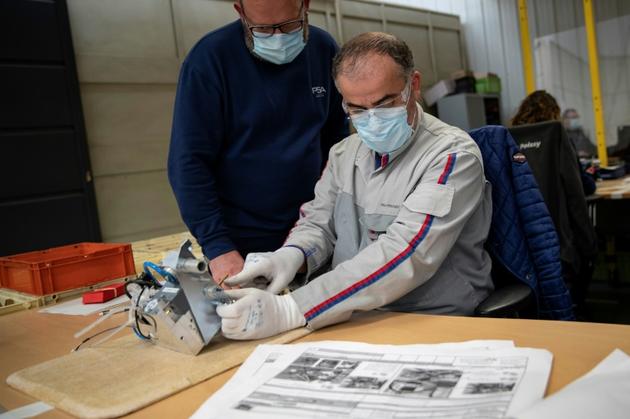 Des employés du groupe automobile PSA assemblent les pièces de respirateurs médicaux, le 15 avril 2020 à l'usine de Poissy, au nord-ouest de Paris [Thomas SAMSON / AFP]