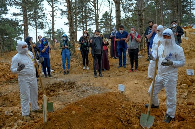 Quelques membres de la famille se recueillent devant la tombe d'un proche décédé du coronavirus au cimetière d'Istanbul, le 21 mai 2020 en Turquie [BULENT KILIC / AFP]
