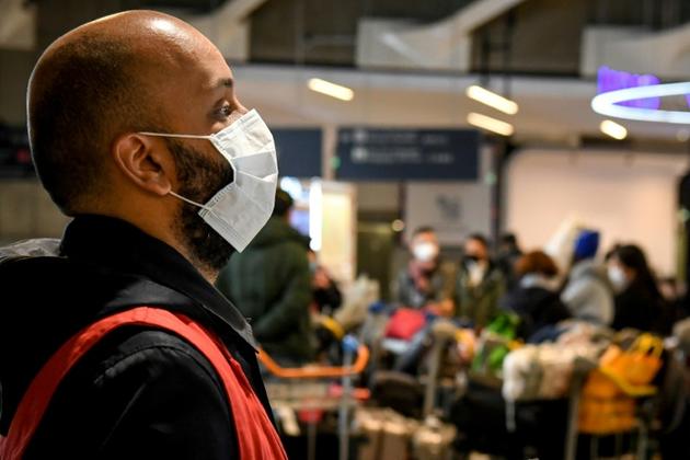 Un employé se tient devant des passagers en provenance de Chine le 26 janvier 2020 à l'aéroport de Roissy [Alain JOCARD / AFP]
